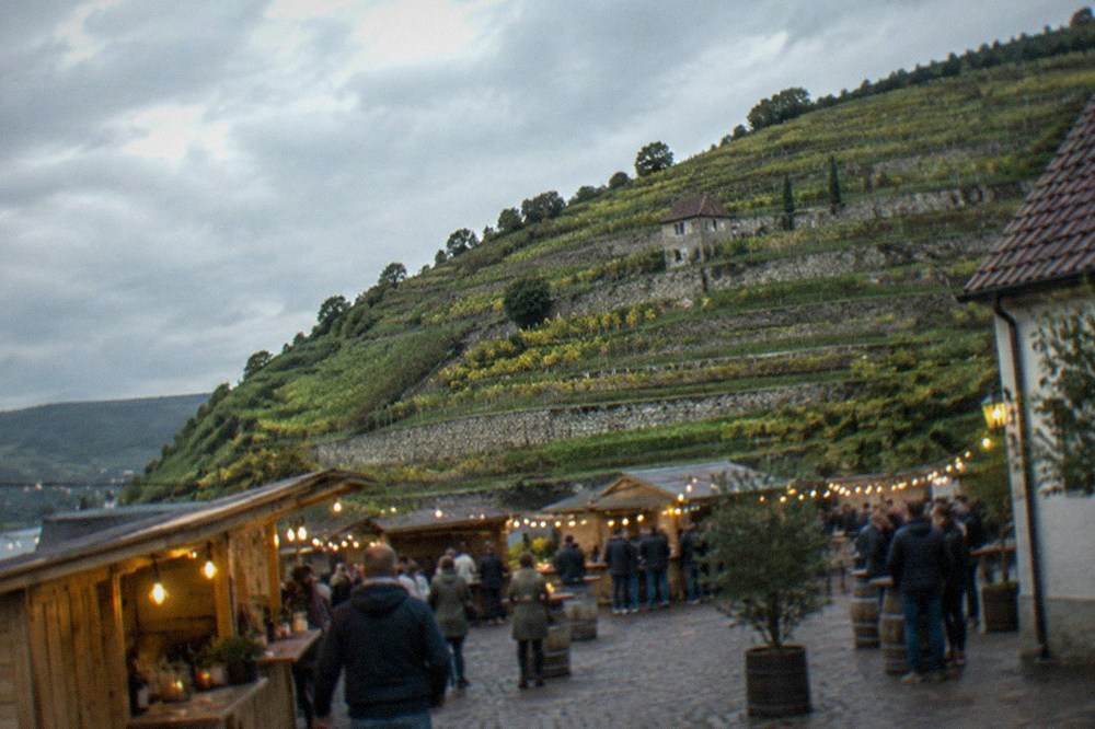 Wooden wine festival stalls with string lights in a town square in the evening