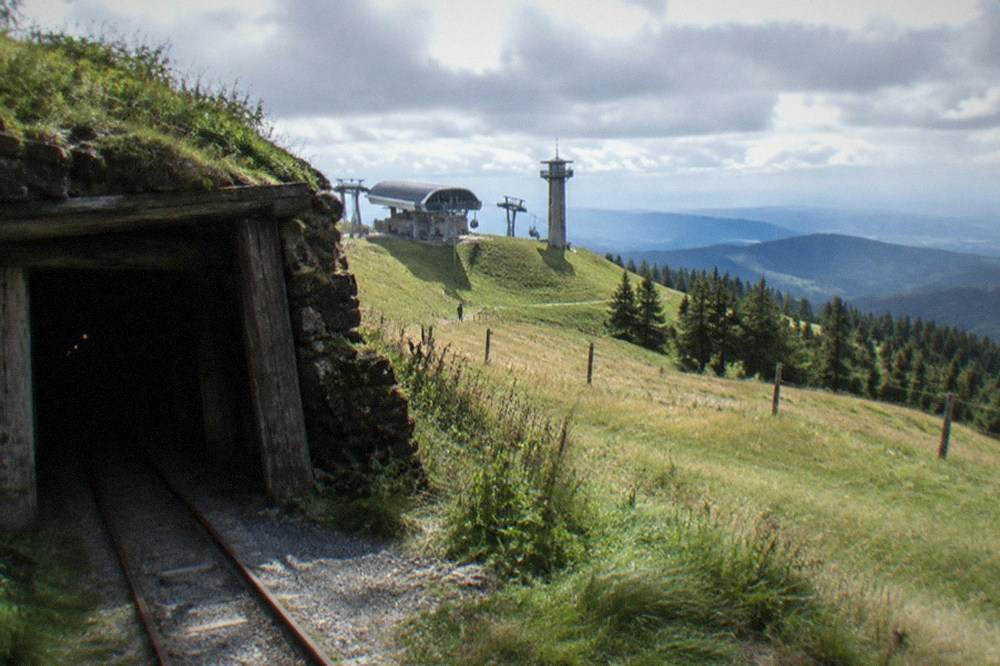 Mine entrance in a hillside with a narrow rail track leading inside