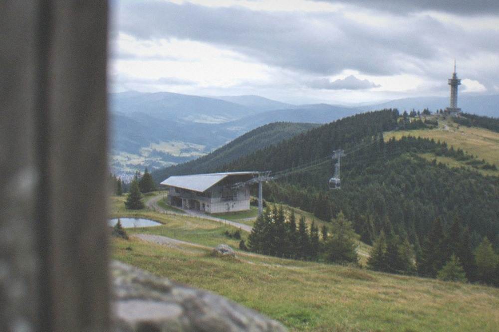 Mountain valley station building with cable car cables rising into forest