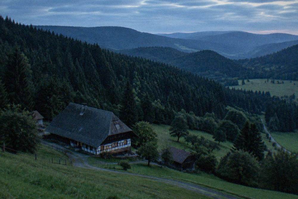 Rolling green meadows and forest edge under a mix of sun and cloud in the Black Forest hills