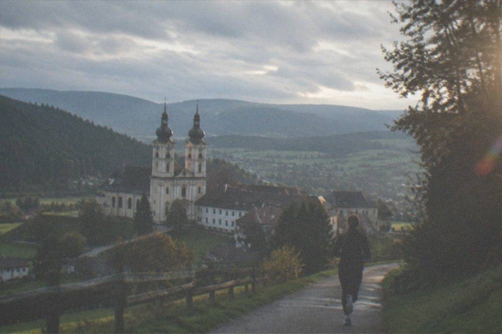 A panoramic view over dark forest ridges toward distant valley villages