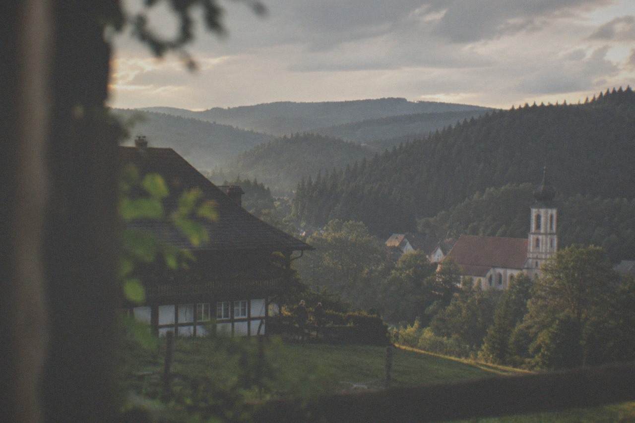 A small Black Forest village with a baroque church tower behind rolling forested hills