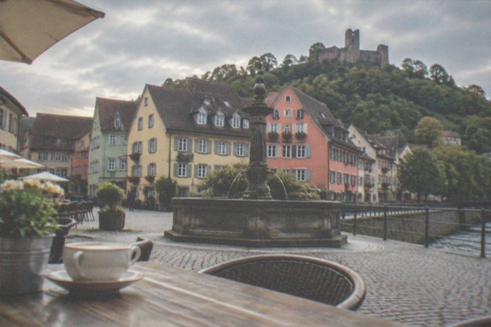 Fountain and café tables on a small market square with painted town houses