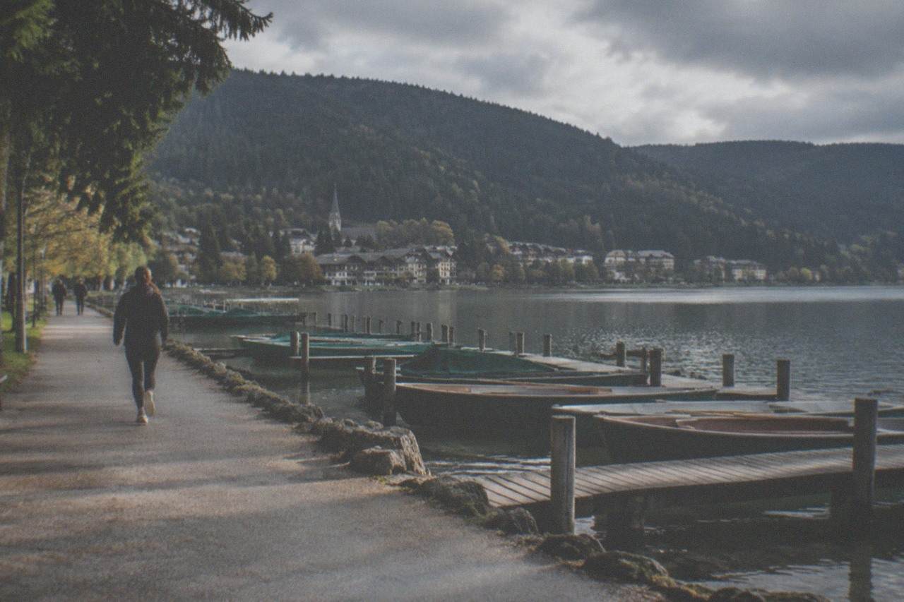 A calm lake surrounded by dark forest hills with a village at the shoreline