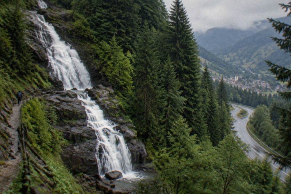 Winding mountain road climbing through conifer forest toward a Black Forest valley town