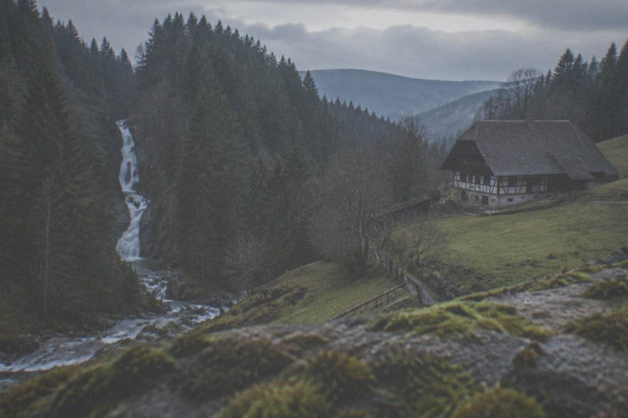 A waterfall dropping in narrow white stages through a steep wooded Black Forest gorge