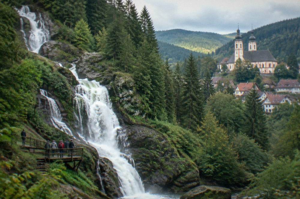 Baroque church towers above a village of red roofs in wooded hills