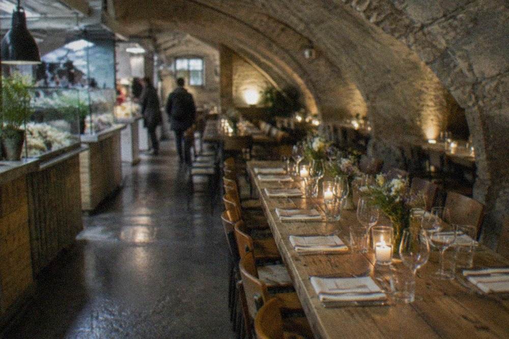 A long restaurant table set for dinner inside a vaulted stone cellar