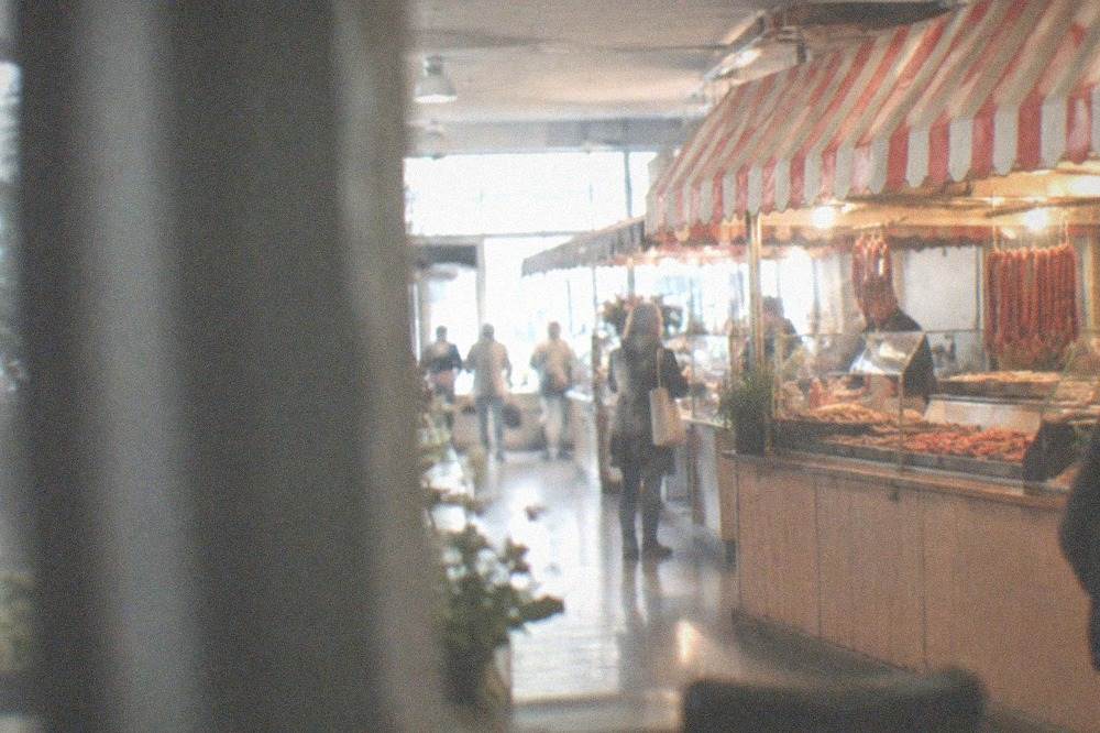A sausage stand with a striped awning lit up against an evening street