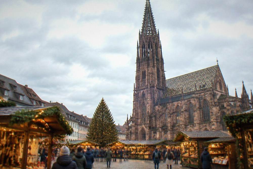 Festively decorated market chalets glowing at dusk on a Freiburg square