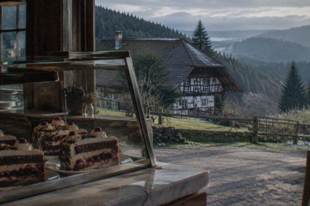 A glass café display case with slices of Black Forest cake on a marble counter