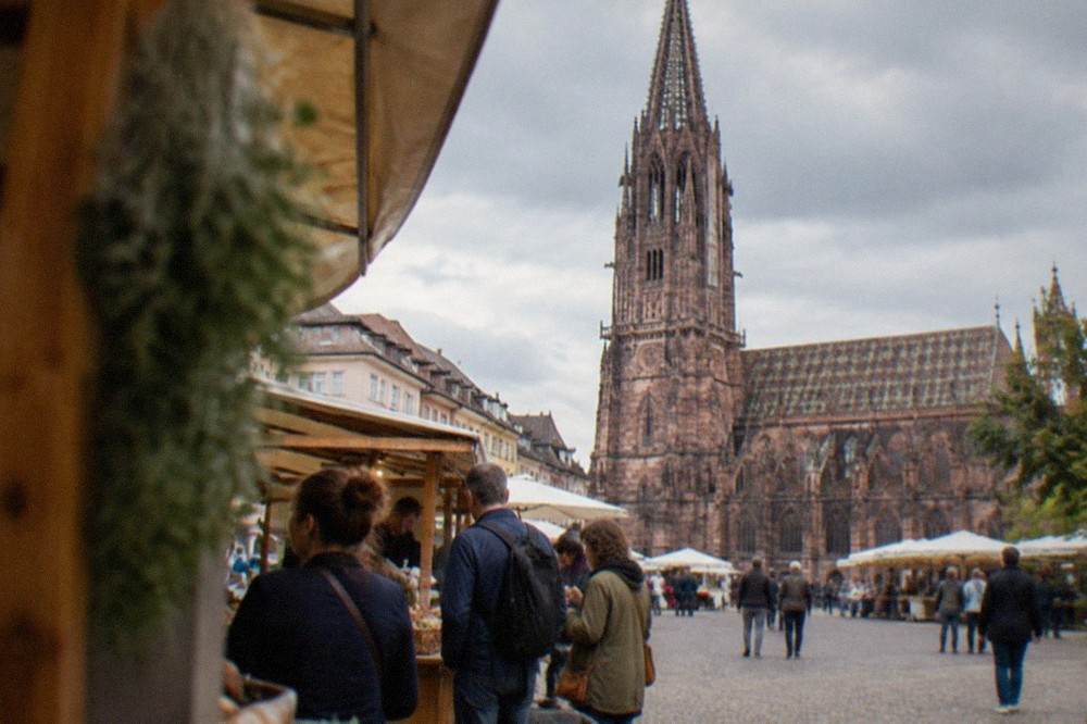 A guided food tour group tasting regional dishes at a market stall in Freiburg