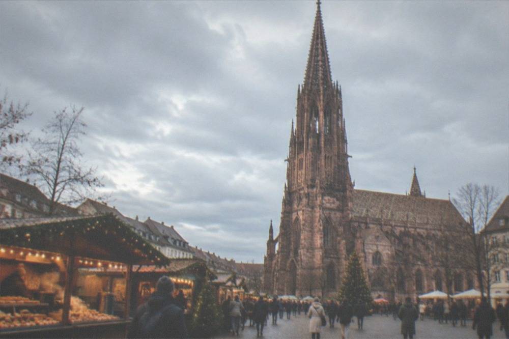 A Christmas market stall with festive bakes and a warm drink under lights in Freiburg old town