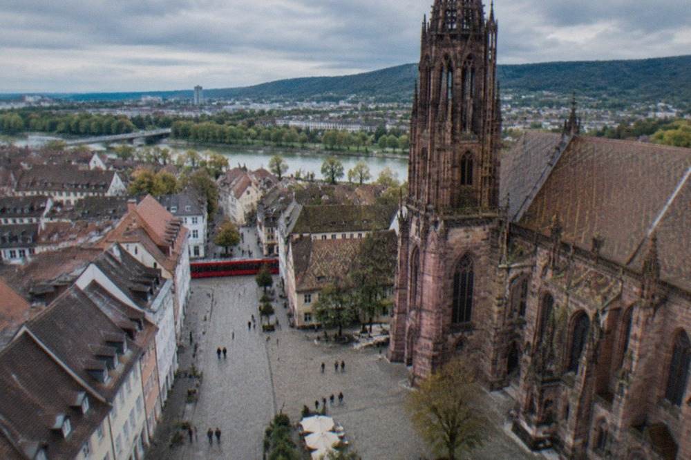 Cobbled pedestrian lane in Freiburg old town with a red tram crossing at the end of the street