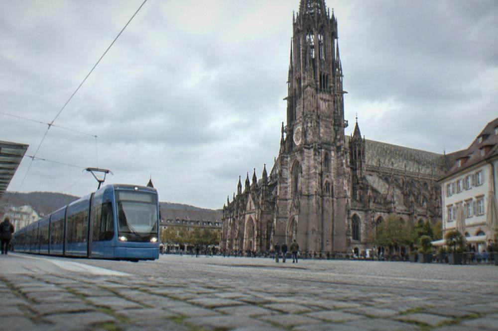 Modern tram stop with level boarding platform and a blue tram arriving in Freiburg