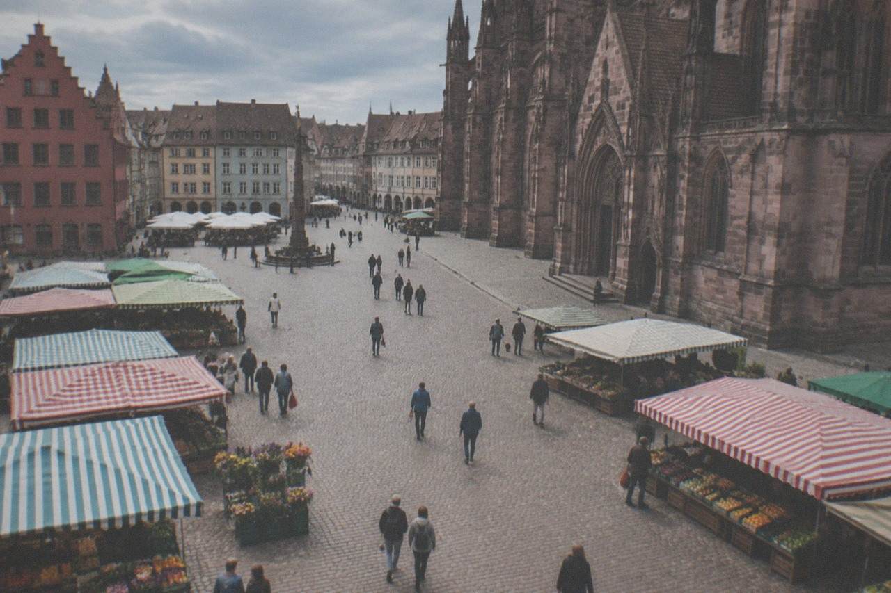 Wide flat square in front of Freiburg's red sandstone minster with market stalls and open paving