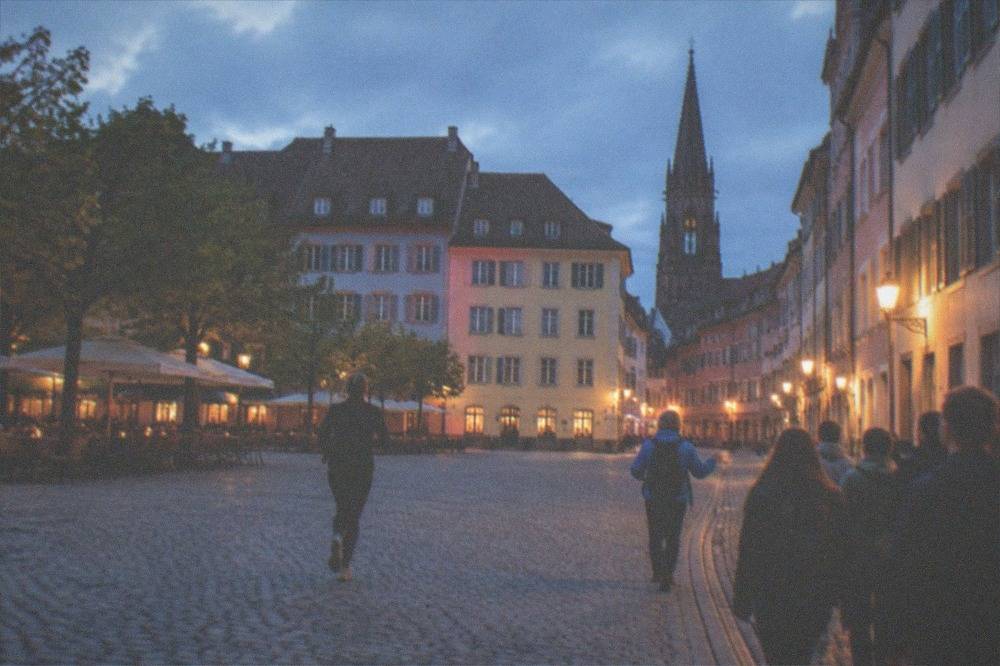Group walking through a lit old town street at night with a guide leading