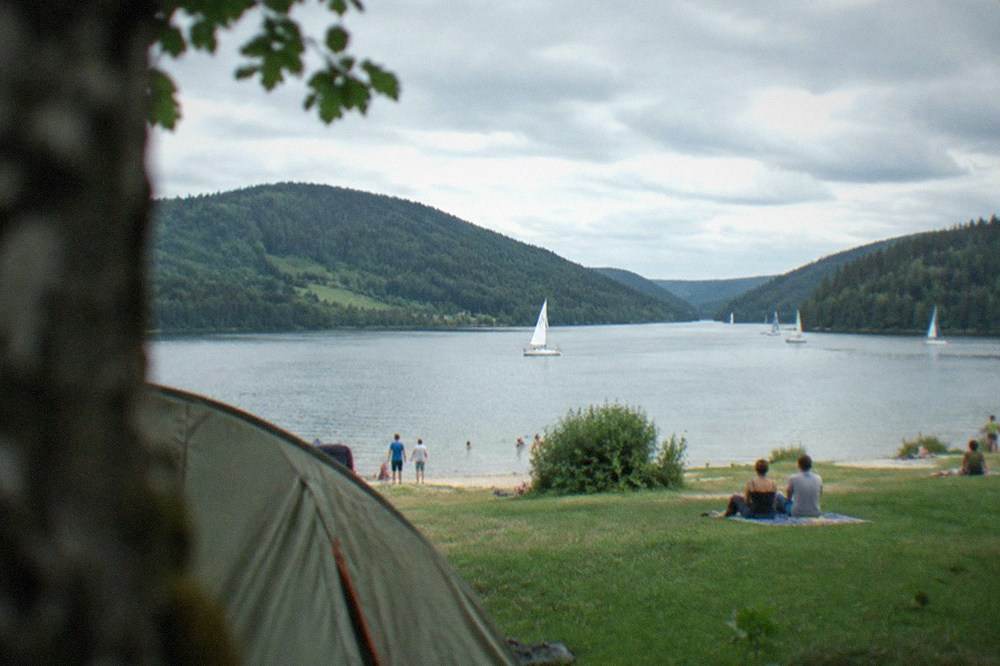 Tents on a green field under a partly cloudy summer sky above the Rhine valley