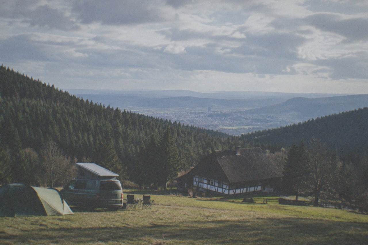 Tent and campervan pitch on a grassy field with the Black Forest hills behind Freiburg in the distance
