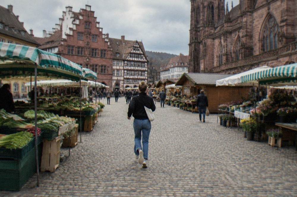 Wooden chalet stalls lined up on a cobbled square in front of old half timbered buildings