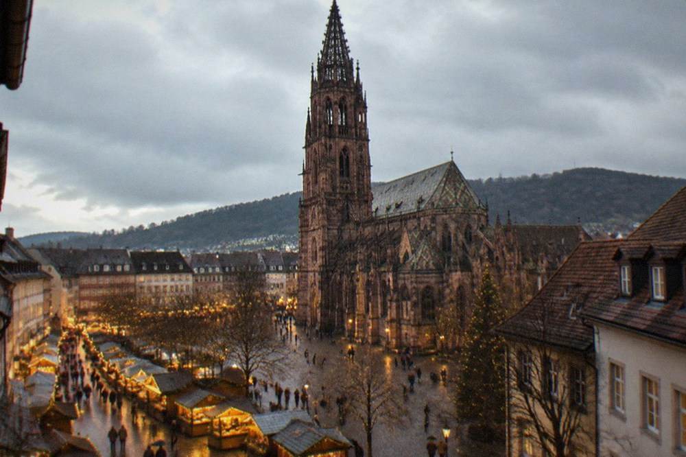 Wooden Christmas market chalets with string lights along a Freiburg street at night