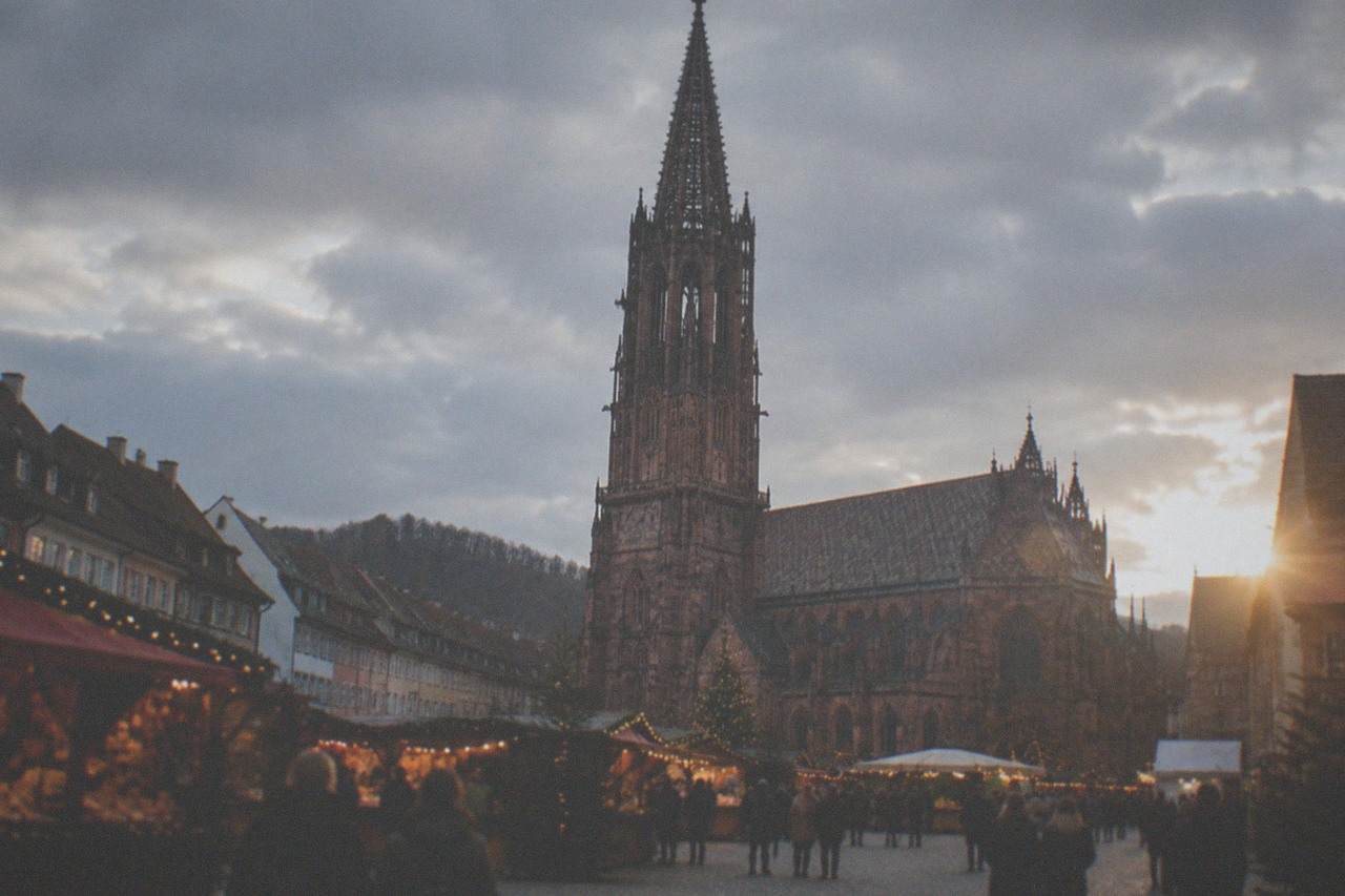 Festively lit square in Freiburg old town at dusk with market stalls