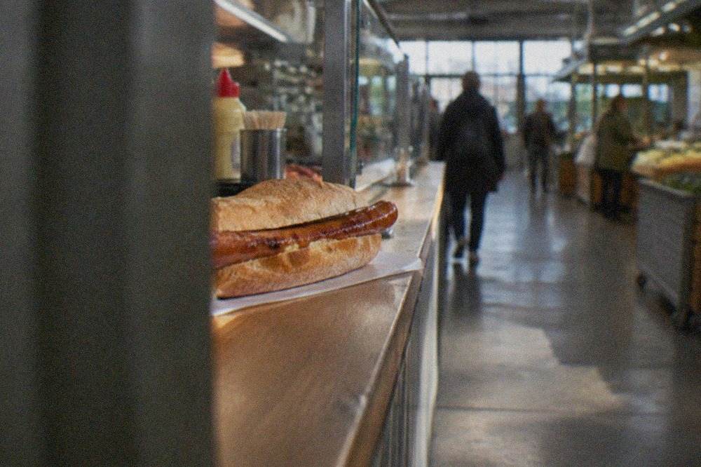 Close view of a long red sausage in a crusty roll on a market stall counter