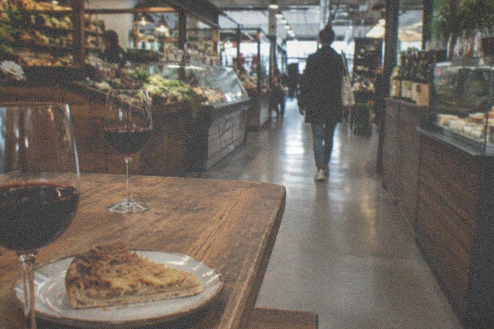 Glasses of red wine on a wooden tavern table beside a slice of onion tart