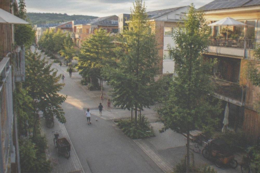 Car-free residential street in Vauban with children playing and trees shading balconies