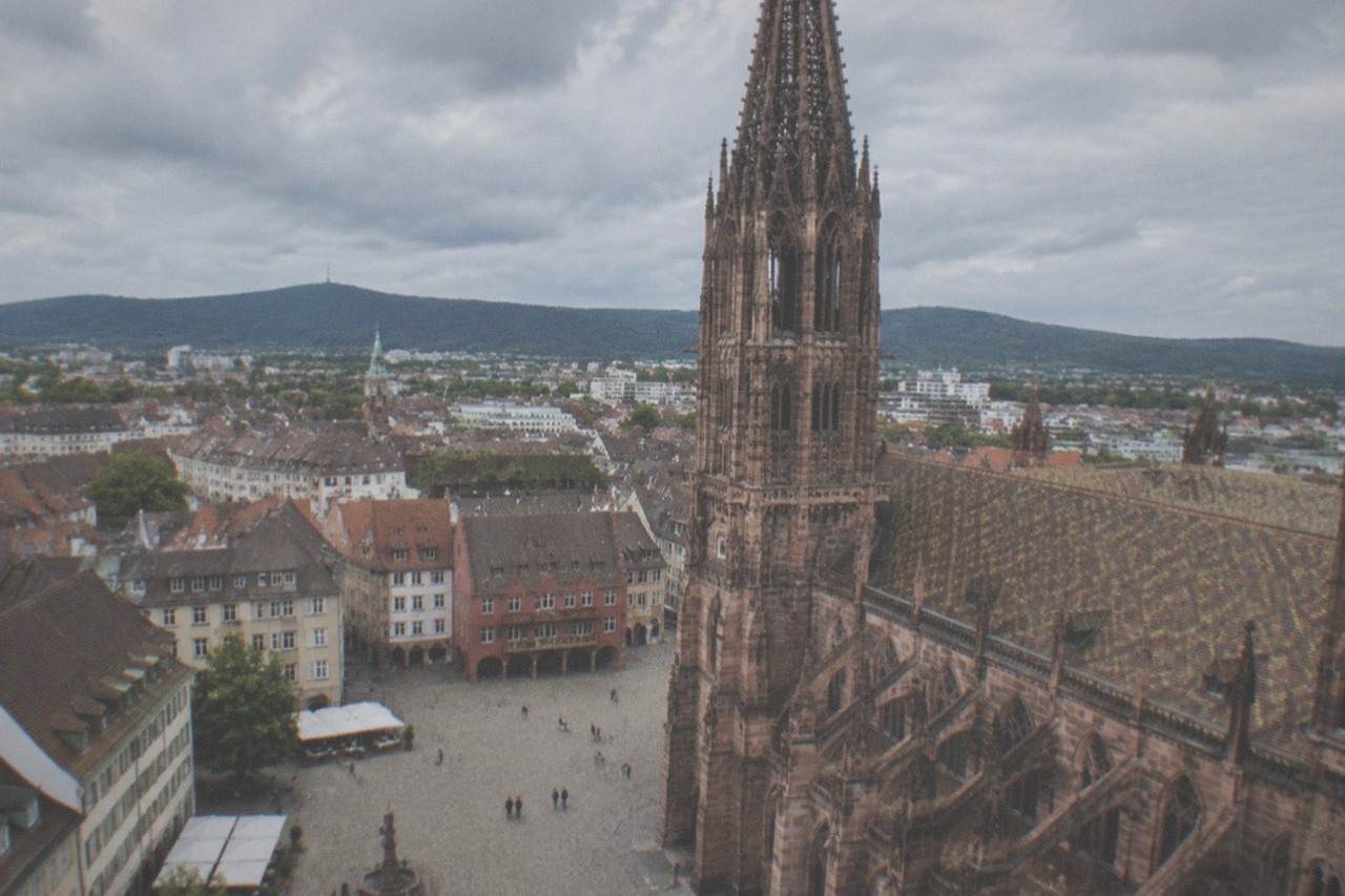 Cobblestone square in Freiburg with the red sandstone minster tower rising above old town roofs