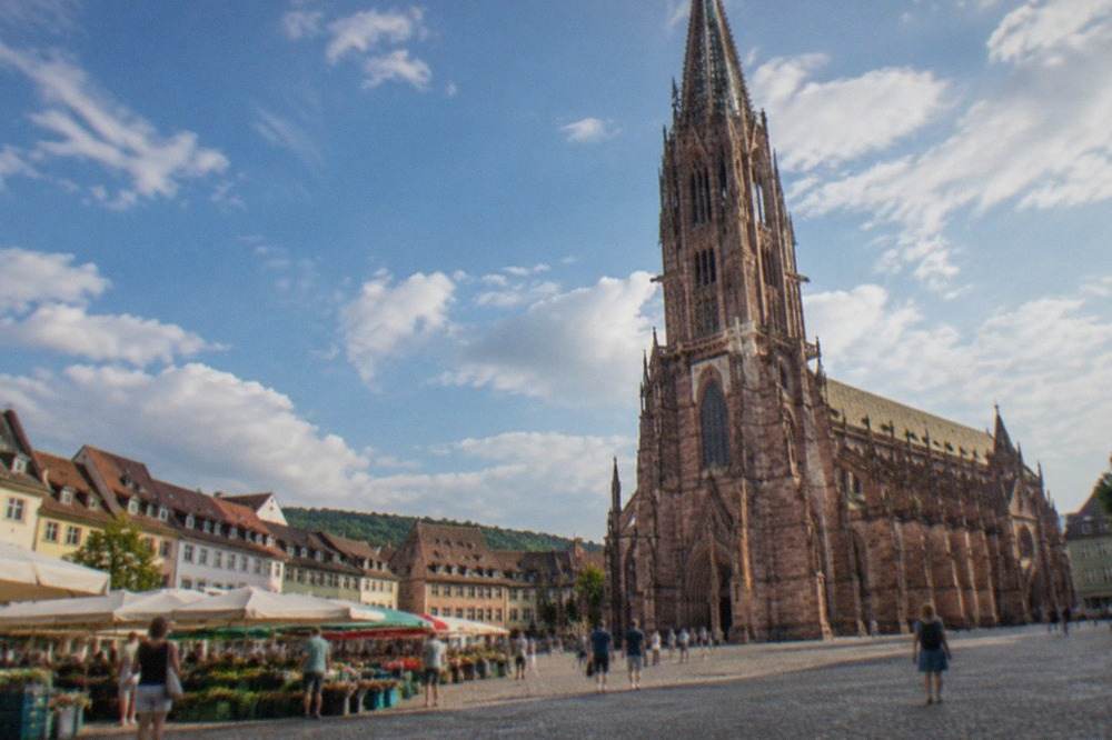 The Freiburg Minster and market square under a bright blue summer sky