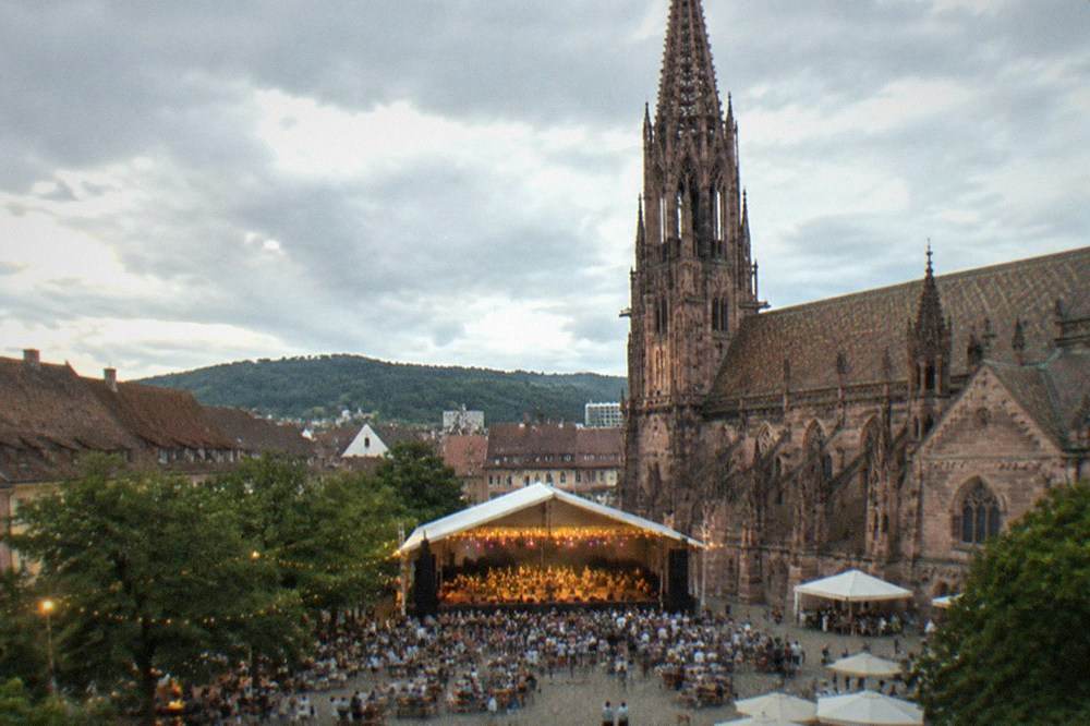 An open-air festival tent stage with string lights set up for a summer evening in Freiburg