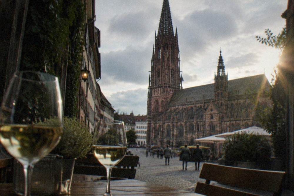 Wine glasses on wooden tables outside a small tavern in a narrow Freiburg lane
