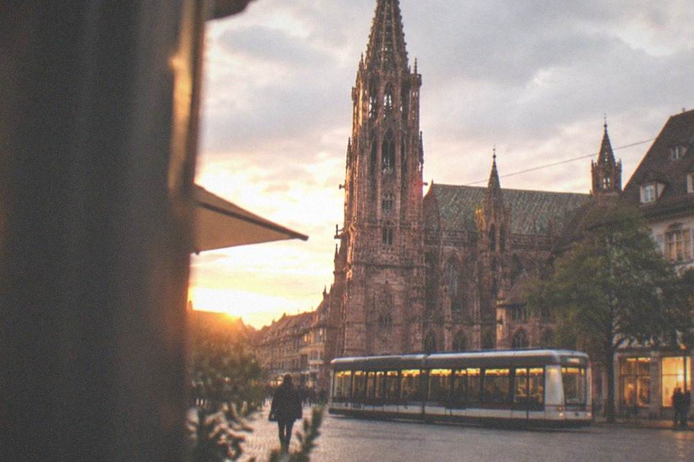 A Freiburg tram passing lit shopfronts on an evening street