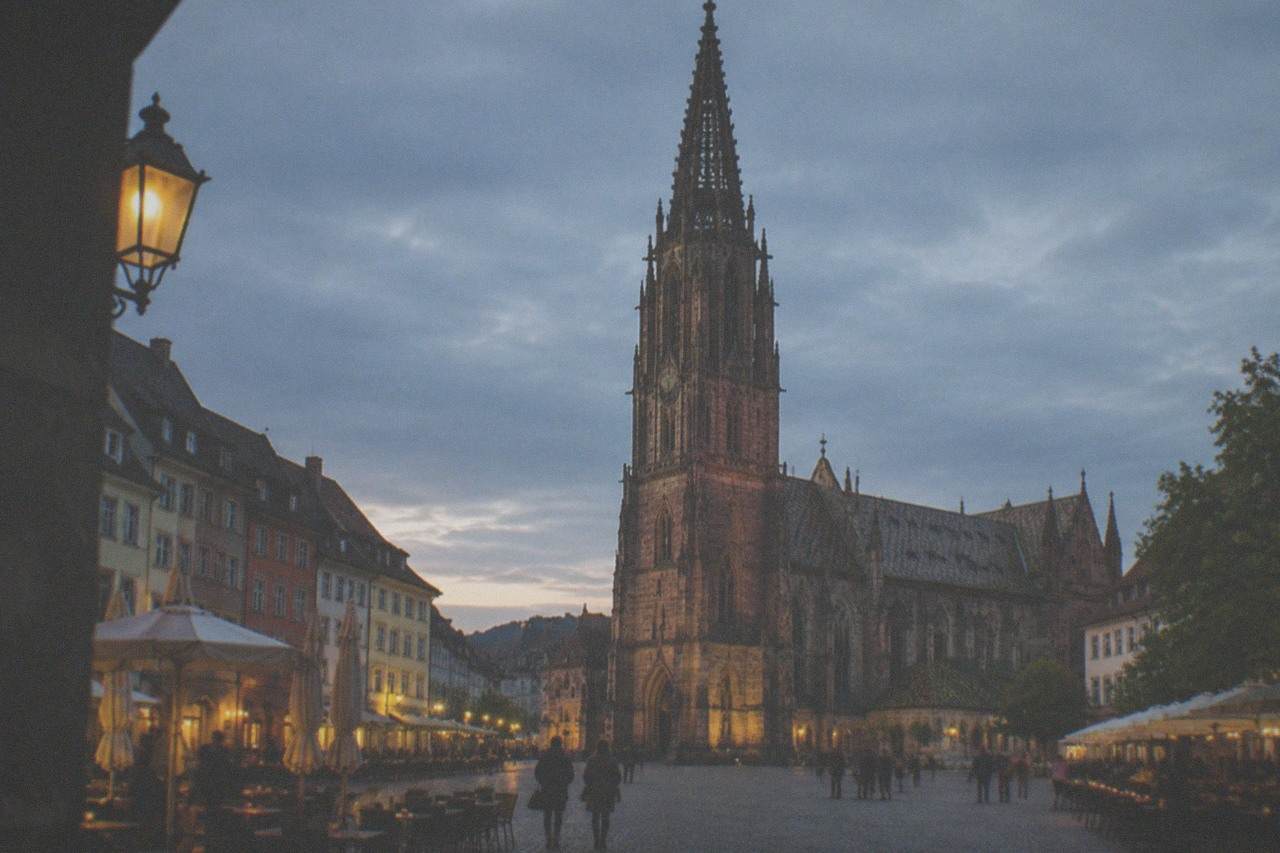 Warm evening light over a Freiburg square lined with pub tables and historic facades