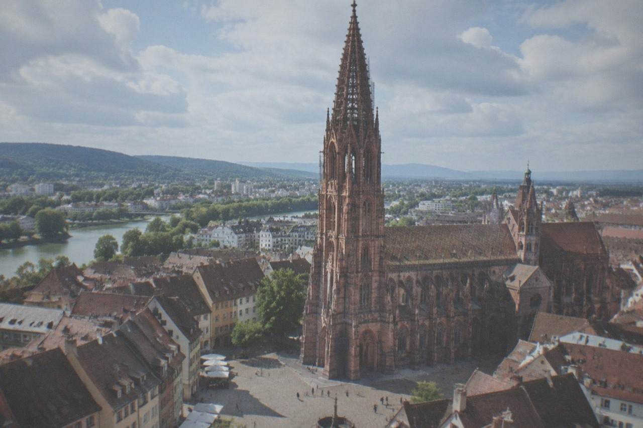 Freiburg old town street with the minster tower rising above tiled rooftops on a clear morning