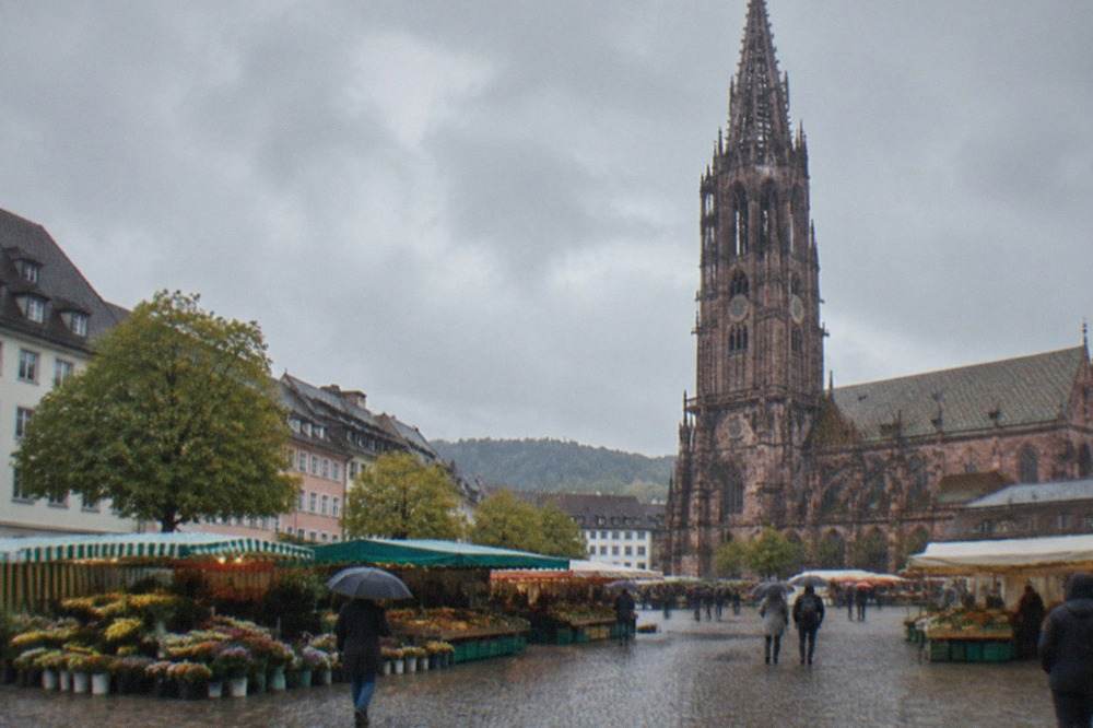 Freiburg Minster tower seen across Münsterplatz with market stalls below