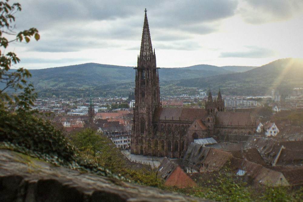 View over Freiburg old town rooftops with the minster and hills beyond from the Schlossberg