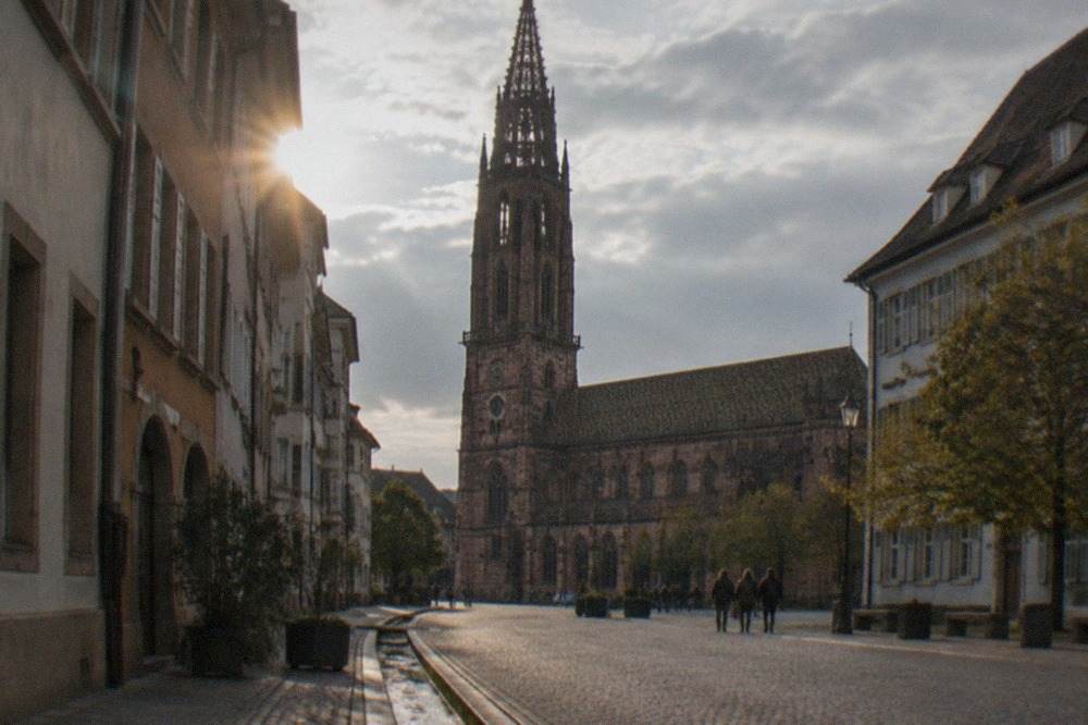 Cobblestone street in Freiburg with historic facades and a small water channel along the gutter