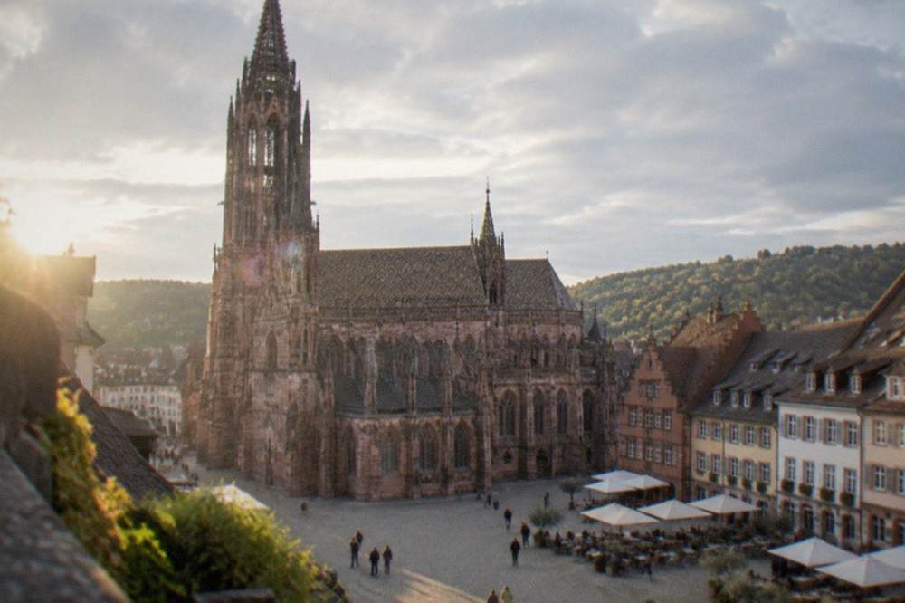 Sunny square in Freiburg with cafe tables and historic guild houses in the background