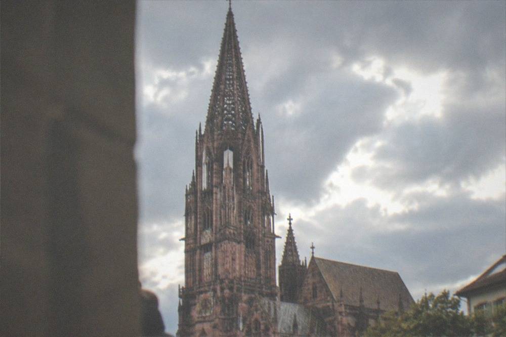 Looking up at the sandstone lattice of the Freiburg Münster tower from Münsterplatz