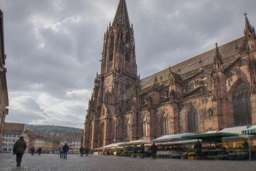 Cobbled square in front of Freiburg Minster with market stalls along the cathedral facade