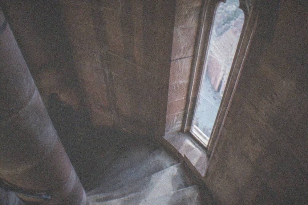 Stone spiral stairway inside a cathedral tower with light from a narrow window