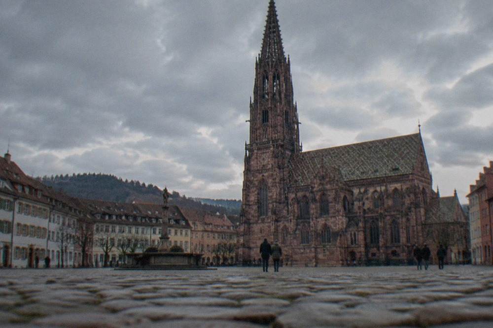 Freiburg old town rooftops under a partly cloudy sky with the minster tower rising above the city