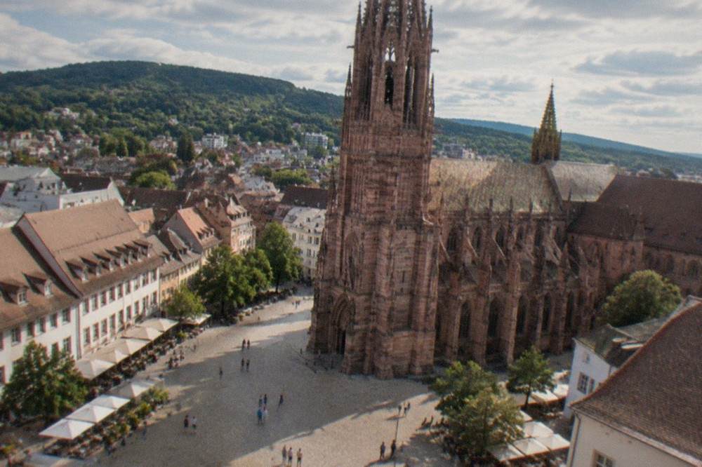 A sunny summer street in Freiburg old town with cafe tables along the pavement
