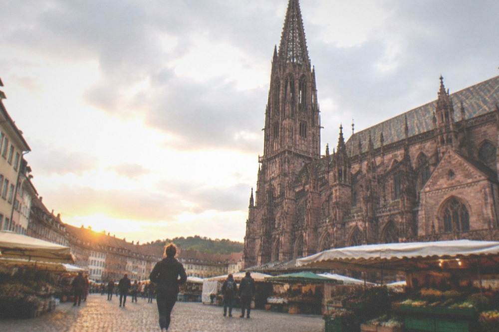 The market square in Freiburg with the red sandstone Minster facade and market stalls along the cobbles