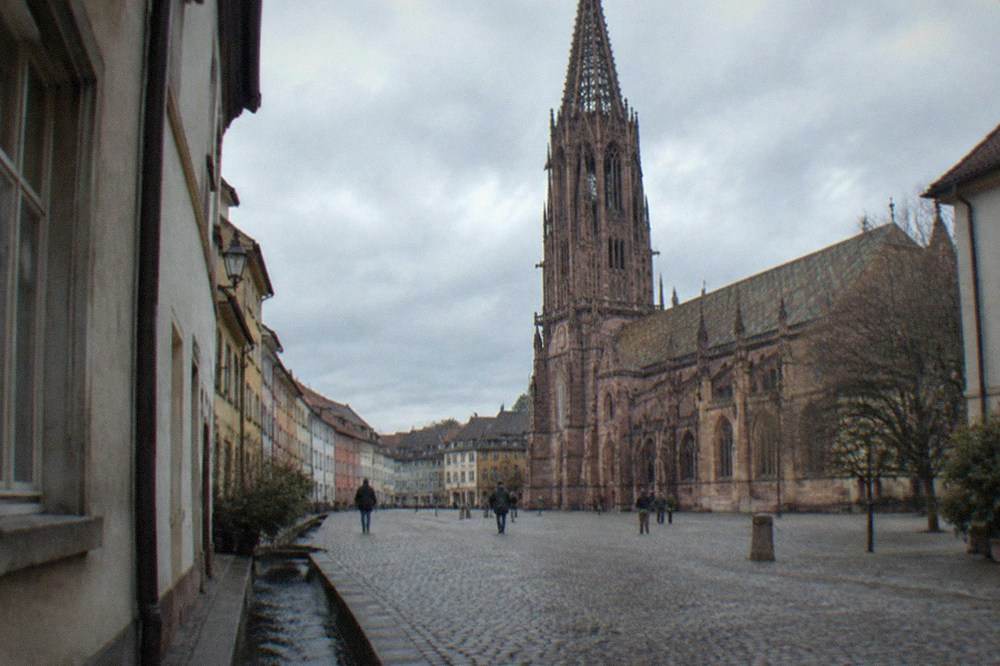 A narrow lane in Freiburg old town with a small water channel running along the curb