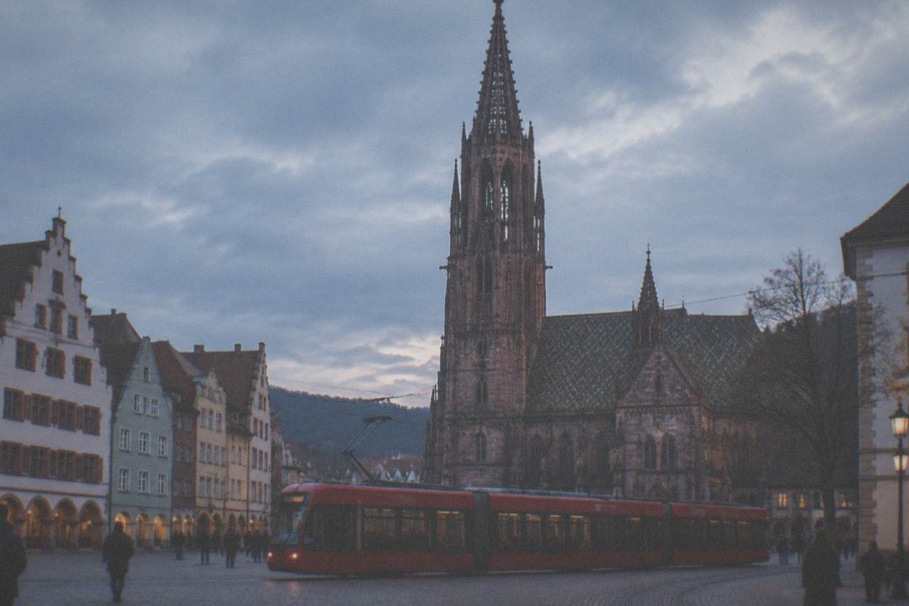 A red Freiburg tram crossing a cobblestone square in front of historic gabled buildings