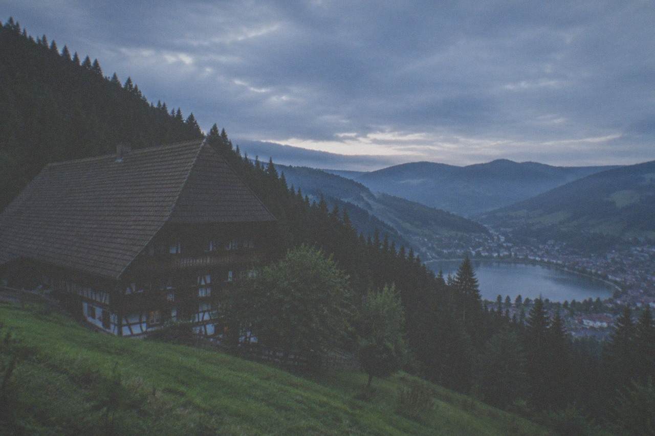 Rolling forested hills of the Black Forest rising above a small lake town on a bright morning