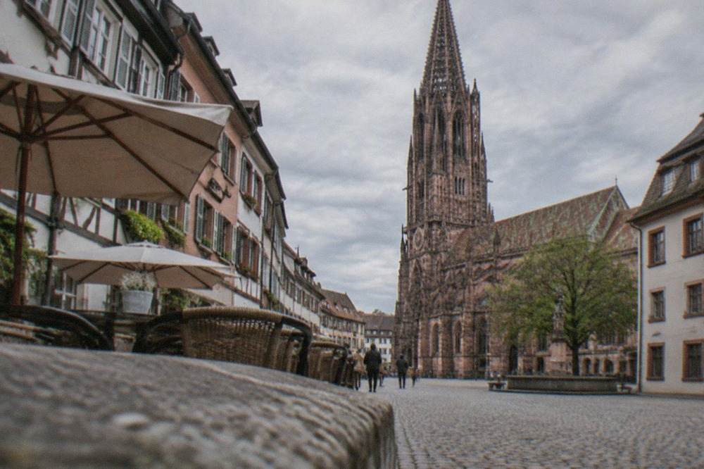 Cobbled lane in Freiburg old town with half-timbered facades and a quiet cafe terrace in early evening